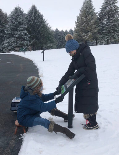two women changing out the storywalk in winter