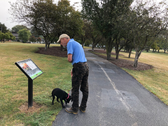 man walking a dog and reading the storywalk story