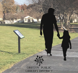 silhouette of parent and child walking past the story walk at the park